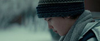 Movie still from “Let Me In” (2010), directed by Matt Reeves – A person wearing a hat looking down at the ground; Close Up shot, Over the shoulder angle