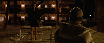 Movie still from “Let Me In” (2010), directed by Matt Reeves – A woman standing on a platform in front of a building; Wide shot, Over the shoulder angle