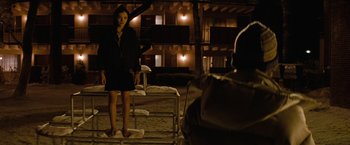 Movie still from “Let Me In” (2010), directed by Matt Reeves – A woman standing on a platform in front of a building; Wide shot, Over the shoulder angle