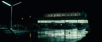 Movie still from “Let Me In” (2010), directed by Matt Reeves – A parking lot at night with cars parked in front of it; Extreme Wide shot, Low angle