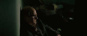 Movie still from “Let Me In” (2010), directed by Matt Reeves – An older man sitting on a couch in a dark room; Close Up shot, Over the shoulder angle