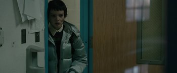 A person standing in front of a door wearing a jacket