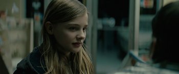 Movie still from “Let Me In” (2010), directed by Matt Reeves – A young girl with long blonde hair looking to her left; Close Up shot, Over the shoulder angle