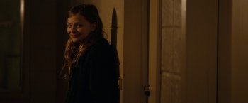 Movie still from “Let Me In” (2010), directed by Matt Reeves – A woman standing in front of a door in the dark; Medium shot, Over the shoulder angle