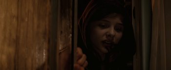 Movie still from “Let Me In” (2010), directed by Matt Reeves – A young girl looking out a window in a dark room; Close Up shot, Low angle