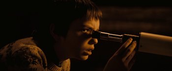 Movie still from “Let Me In” (2010), directed by Matt Reeves – A young boy looking through a microscope at something; Close Up shot, High angle