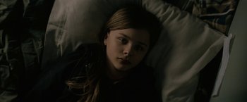 Movie still from “Let Me In” (2010), directed by Matt Reeves – A girl laying in a bed looking at the camera; Close Up shot, High angle