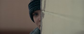 Movie still from “Let Me In” (2010), directed by Matt Reeves – A young boy with a hat on looking over a wall; Extreme Close Up shot, Over the shoulder angle