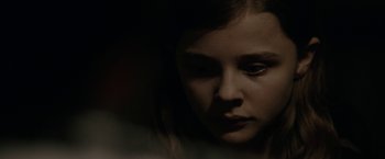 Movie still from “Let Me In” (2010), directed by Matt Reeves – A young girl is looking at the camera; Close Up shot, Low angle