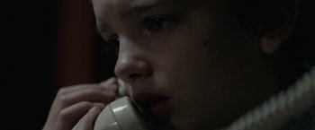 Movie still from “Let Me In” (2010), directed by Matt Reeves – A young boy holding a phone up to his face; Extreme Close Up shot, Low angle