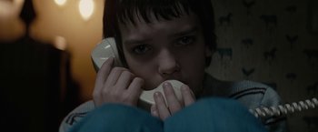 Movie still from “Let Me In” (2010), directed by Matt Reeves – A young boy holding a phone to his face; Close Up shot, Low angle