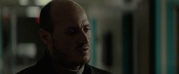 Movie still from “Let Me In” (2010), directed by Matt Reeves – A man with a bald head looking to his left; Close Up shot, Low angle