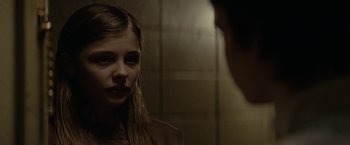 Movie still from “Let Me In” (2010), directed by Matt Reeves – A young girl looking into a mirror in a bathroom; Close Up shot, Over the shoulder angle
