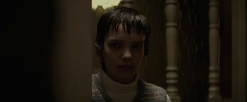 Movie still from “Let Me In” (2010), directed by Matt Reeves – A person with short black hair is standing in front of a wall; Close Up shot, Low angle