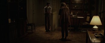 Movie still from “Let Me In” (2010), directed by Matt Reeves – A man and a woman standing in a dark room; Wide shot, High angle