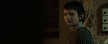 Movie still from “Let Me In” (2010), directed by Matt Reeves – A young person with short black hair is looking at the camera; Close Up shot, Over the shoulder angle