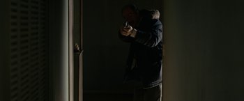 Movie still from “Let Me In” (2010), directed by Matt Reeves – A man in a black jacket is holding a knife; Medium shot, Over the shoulder angle