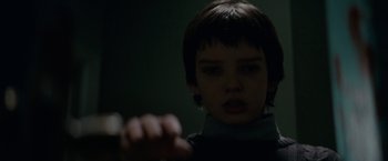 Movie still from “Let Me In” (2010), directed by Matt Reeves – A young boy looking at the camera in a dark room; Close Up shot, Over the shoulder angle