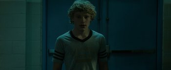 Movie still from “Let Me In” (2010), directed by Matt Reeves – A young man with curly blonde hair wearing a t - shirt; Medium shot, Low angle