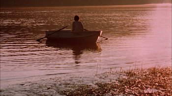 Movie still from “Let's Scare Jessica to Death” (1971), directed by John D. Hancock – A person in a boat on a body of water at sunset; Wide shot, High angle