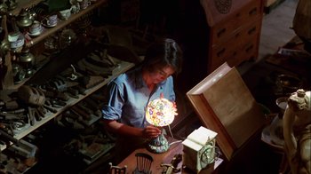 Movie still from “Let's Scare Jessica to Death” (1971), directed by John D. Hancock – A woman working on a lamp in a room; Medium shot, High angle