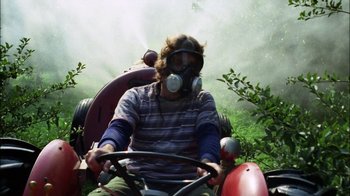 Movie still from “Let's Scare Jessica to Death” (1971), directed by John D. Hancock – A man wearing a gas mask driving a tractor; Medium shot, Low angle