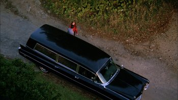 Movie still from “Let's Scare Jessica to Death” (1971), directed by John D. Hancock – An aerial view of a woman standing in front of a limo; Extreme Wide shot, High angle