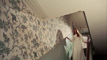Movie still from “Let's Scare Jessica to Death” (1971), directed by John D. Hancock – A woman in a white dress standing on a staircase; Wide shot, High angle