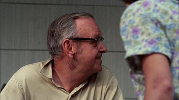 Movie still from “Let's Scare Jessica to Death” (1971), directed by John D. Hancock – An older man wearing glasses and a tan shirt; Close Up shot, Over the shoulder angle