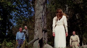 Movie still from “Let's Scare Jessica to Death” (1971), directed by John D. Hancock – A woman standing in front of a tree in the woods; Wide shot, Low angle