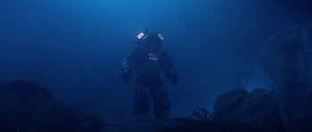Movie still from “Leviathan” (1989), directed by George P. Cosmatos – A man standing in the water wearing a diving suit; Wide shot, Low angle
