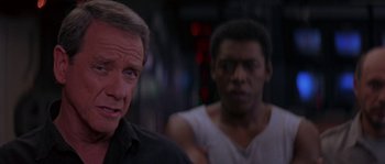 Movie still from “Leviathan” (1989), directed by George P. Cosmatos – A man standing next to another man in a white shirt; Close Up shot, Over the shoulder angle