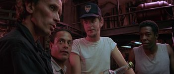 Movie still from “Leviathan” (1989), directed by George P. Cosmatos – A group of men standing next to each other in a room; Close Up shot, Low angle