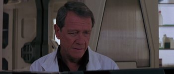 Movie still from “Leviathan” (1989), directed by George P. Cosmatos – An older man wearing a white lab coat looking at a computer screen; Close Up shot, Low angle