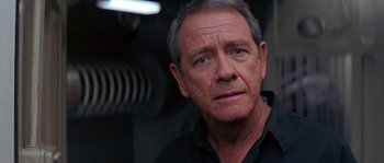 Movie still from “Leviathan” (1989), directed by George P. Cosmatos – An older man in a black shirt looking at the camera; Close Up shot, Over the shoulder angle