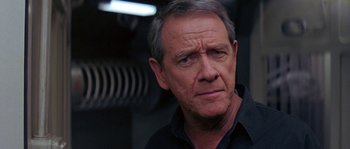 Movie still from “Leviathan” (1989), directed by George P. Cosmatos – An older man in a black shirt is looking at the camera; Close Up shot, Over the shoulder angle