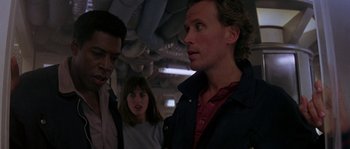 Movie still from “Leviathan” (1989), directed by George P. Cosmatos – A group of people standing next to each other in a room; Close Up shot, Over the shoulder angle