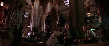 Movie still from “Leviathan” (1989), directed by George P. Cosmatos – A group of men sitting around a building; Wide shot, Low angle
