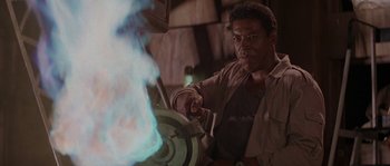 Movie still from “Leviathan” (1989), directed by George P. Cosmatos – A man in brown shirt and brown jacket holding a metal object; Medium shot, Low angle