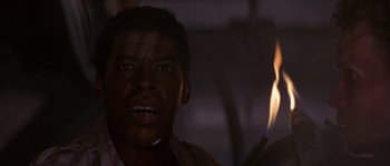 Movie still from “Leviathan” (1989), directed by George P. Cosmatos – A person with a fire in the background; Close Up shot, Low angle