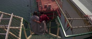 Movie still from “Leviathan” (1989), directed by George P. Cosmatos – Two people are sitting on the stairs of a dock; Wide shot, Overhead angle