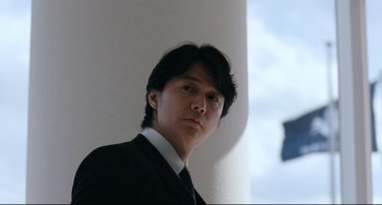 Movie still from “Like Father, Like Son” (2013), directed by Kore-eda Hirokazu – A man wearing a suit and tie standing in front of a wall; Close Up shot, Low angle