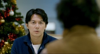 Movie still from “Like Father, Like Son” (2013), directed by Kore-eda Hirokazu – A man looking at the camera while sitting in front of another man; Close Up shot, Over the shoulder angle