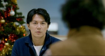 Movie still from “Like Father, Like Son” (2013), directed by Kore-eda Hirokazu – A man sitting in front of another man in front of a mirror; Close Up shot, Over the shoulder angle