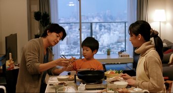 Movie still from “Like Father, Like Son” (2013), directed by Kore-eda Hirokazu – Three people sitting at a table with a bowl of food and chopsticks in front of them; Medium shot, Over the shoulder angle