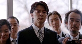 Movie still from “Like Father, Like Son” (2013), directed by Kore-eda Hirokazu – A man wearing a suit and tie standing next to another man; Medium shot, Low angle