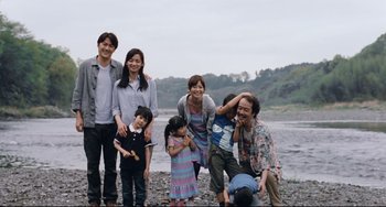 Movie still from “Like Father, Like Son” (2013), directed by Kore-eda Hirokazu – A group of people posing for a picture near a body of water; Medium shot, Low angle