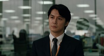 Movie still from “Like Father, Like Son” (2013), directed by Kore-eda Hirokazu – A man wearing a suit and tie in a room; Close Up shot, Over the shoulder angle