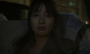 Movie still from “Like Someone in Love” (2012), directed by Abbas Kiarostami – A woman sitting in a chair looking at the camera; Close Up shot, Over the shoulder angle