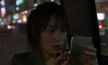 Movie still from “Like Someone in Love” (2012), directed by Abbas Kiarostami – A young woman using a cell phone while sitting in a car; Close Up shot, Over the shoulder angle